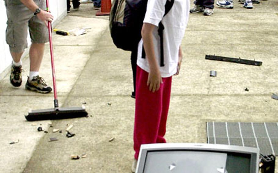 Eighth-grader Geoffrey Boudreaux checks out the remains of the TV as cleanup gets under way.