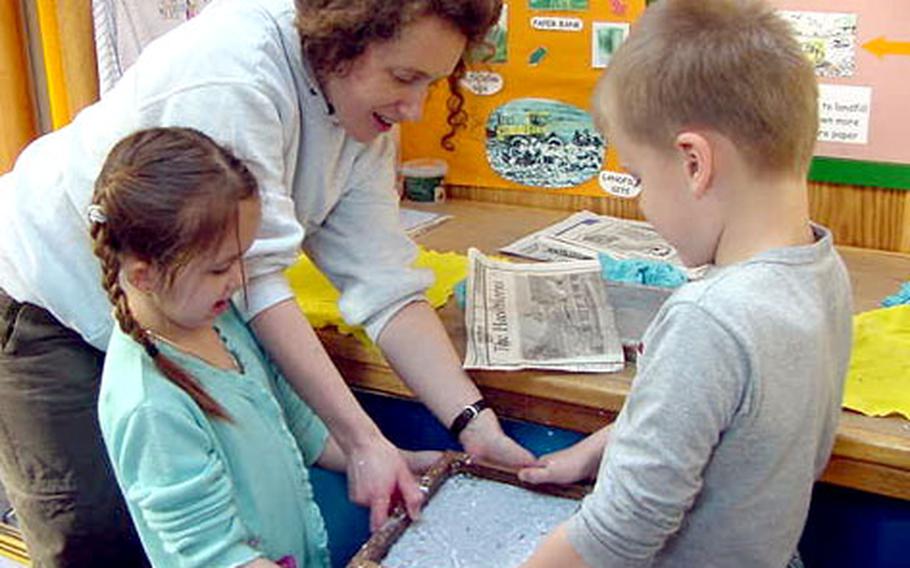 Croughton American School first-graders Kaleigh Dandeneau and Thomas Alto make recycled paper with Jayne Wingad, a Northmoor Trust project officer, during a visit to the Wild Waste Show Bus this week.