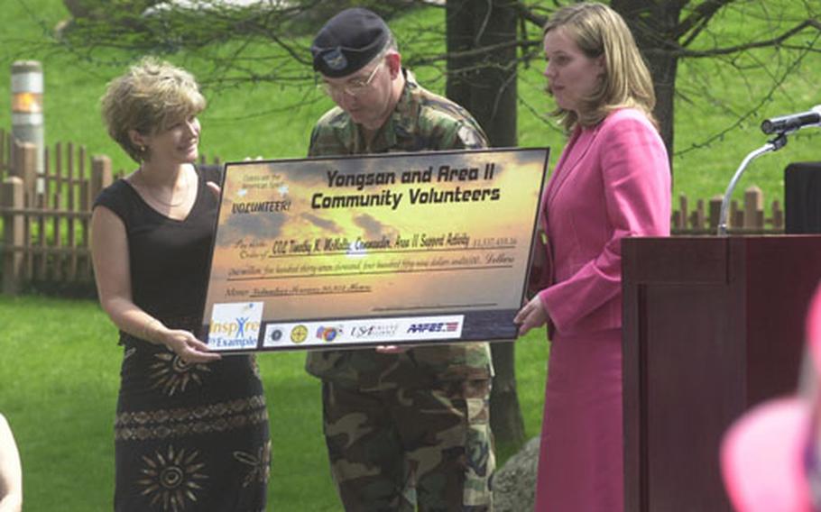 Julie McRee, volunteer of the year, Col. Timothy McNulty and youth volunteer of the year Amy Yarbrough hold a mock check Wednesday representing the $1.5 million the Area II command saved through the help of more than 1,400 volunteers over the last year.