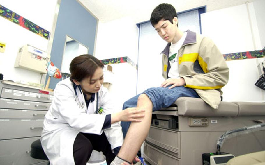 Intern Yukako Tachibana examines Edgar Walker’s knee in the pediatrics clinic at Yokosuka Naval Hospital during a recent appointment.