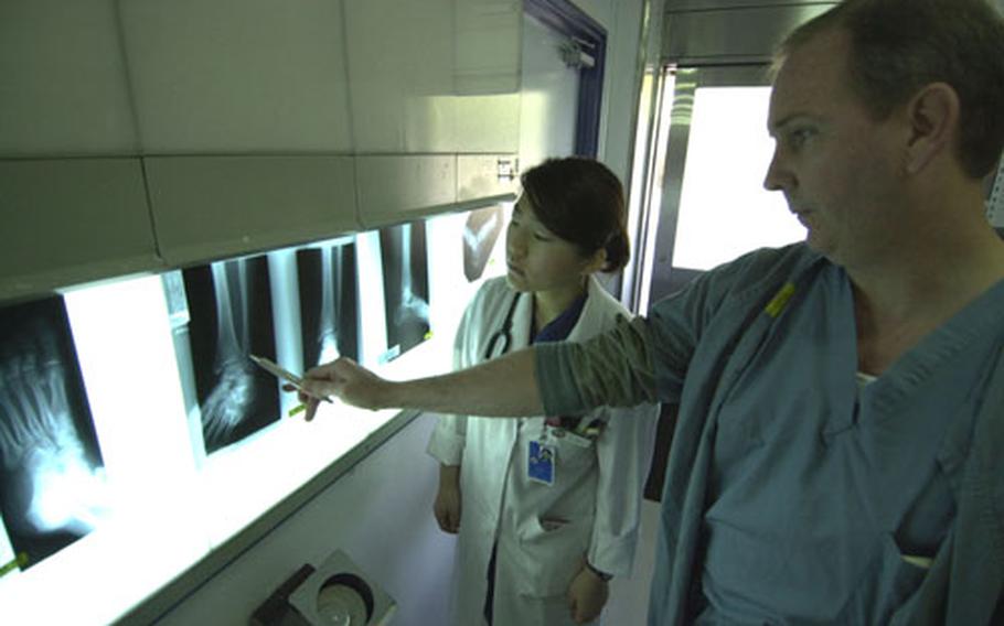 Intern Mariko Saso studies X-rays with Lt. Cdr. Robert Donovan at the Yokosuka Naval Hospital recently.
