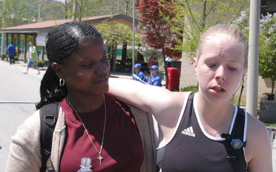 Spc. Heather George, who works with the Camp Casey-based 702nd Main Support Battalion, is assisted by a friend after winning the woman's 8th Army Marathon on Saturday.