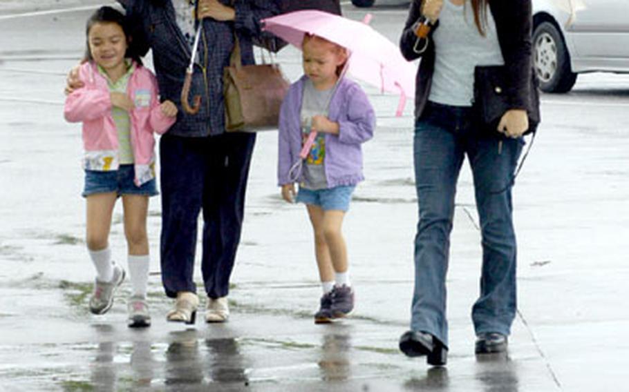 From left, Angel Renfield, 7, her mother, Tina, sister Ana, 4, and grandmother, Fumiko Mueller, brave the rain Tuesday on Camp Foster, Okinawa. Okinawa officials are hoping to make it through to the island’s rainy season, which starts in early May, without water rationing.