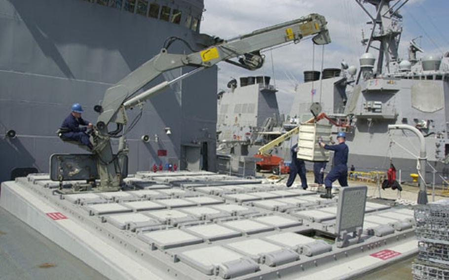 Petty Officer 2nd Class Scott Larson (far left), lowers a Vertical Launch System component to the deck of USS O&#39;Brien with assistance of Petty Officers 2nd Class John Linke (hidden middle) and Mark Wilson (right). The O&#39;Brien sailors were removing the VLS system components in preparation for the ship&#39;s decommissioning.
