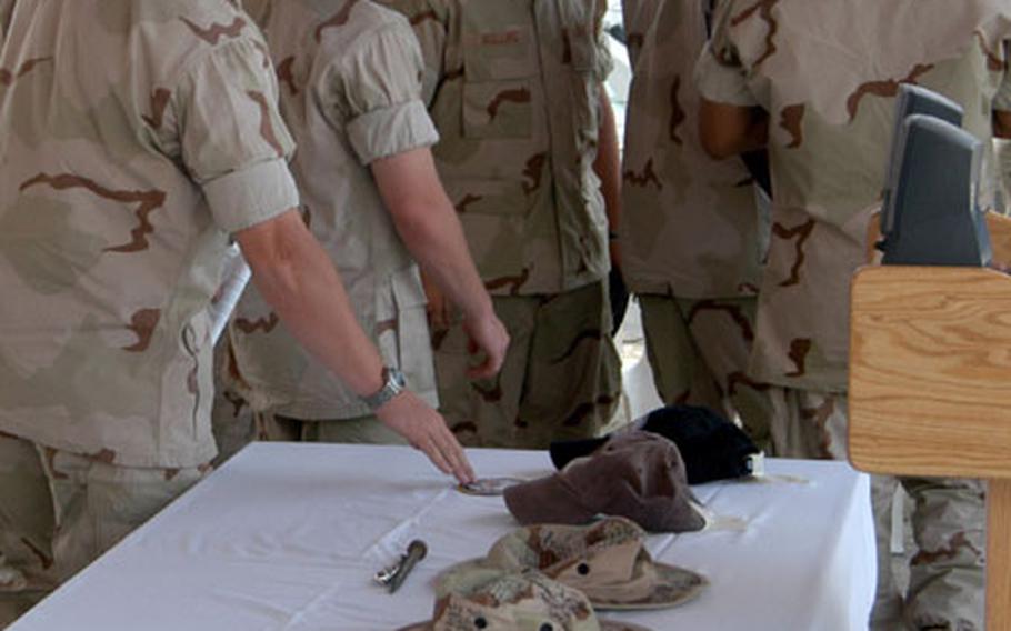 Members of USS Firebolt's crew solemnly touch the uniform covers of their fallen comrades at a memorial service for Petty Officer Michael J. Pernaselli, Petty Officer Christopher E. Watts, and U.S. Coast Guardsman Nathan Bruckenthal. They were killed when a fishing boat they were preparing to board exploded near the Khawr Al Amaya Oil Terminal in the North Arabian Gulf.