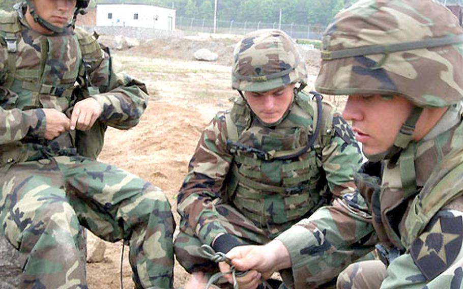 Spc. Jason Trudeau, Spc Price Neal, and Pfc. Daniel Sharon, left to right, of the 2nd Engineer Battalion tie det-cords at Warrior Valley.