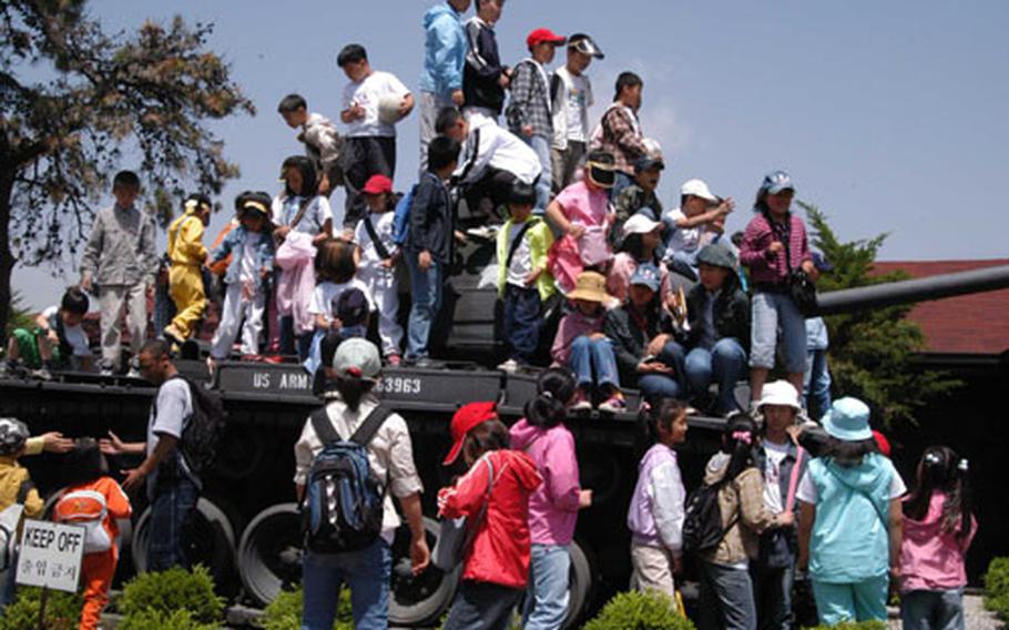 Children from Bojang school, near Rodriguez Range in Area One, enjoyed climbing on this tank during a visit to Camp Red Cloud on Tuesday.