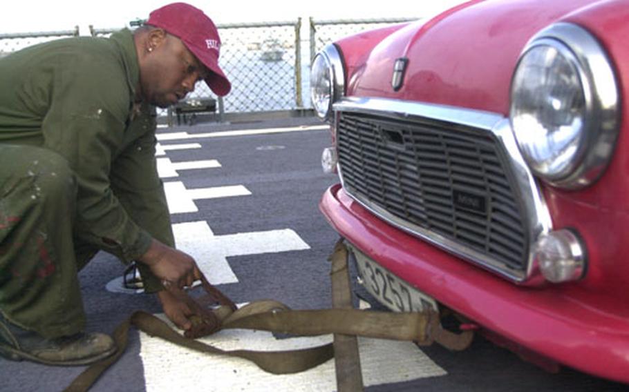 Willie Wiggins, a civilian seaman aboard the USNS Patuxent, straps a Mini to the deck of the ship. The oiler is transporting personal cars, a plane and household goods as part of "Opportune Lift," a little-known program in which eligible personnel overseas can transport good on Navy ships on a space-available basis.