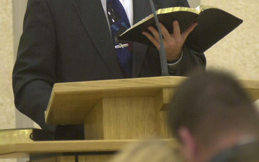 Navy Lt. Scott McKenzie officiates Sunday service at the Church of Jesus Christ of Latter-day Saints in El Puerto de Santa Maria, Spain, as a couple listens. McKenzie juggles a successful career as a Navy environmental health officer and as leader of the local Mormon church.