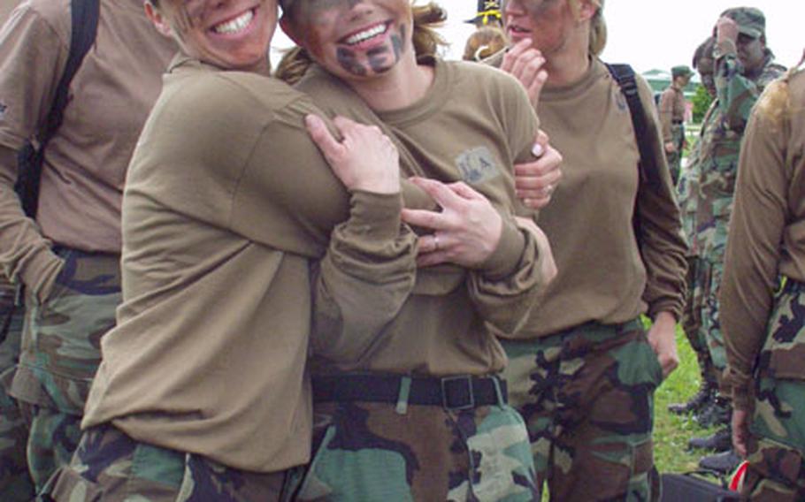 Julie Murray, left, and Adrianne Thrailkill, members of the Homefront Honeys team from the 1/4 Cavalry's Troop A, grab a hug while surrounded by teammates during a break in Saturday's Ladies Spur Ride. The event, for wives of soldiers in the 1/4 Cavalry and other 1st Infantry Division units based in Schweinfurt, Germany, was a scaled-down version of the daylong test of soldiering skills through which cavalry troopers earn their spurs.