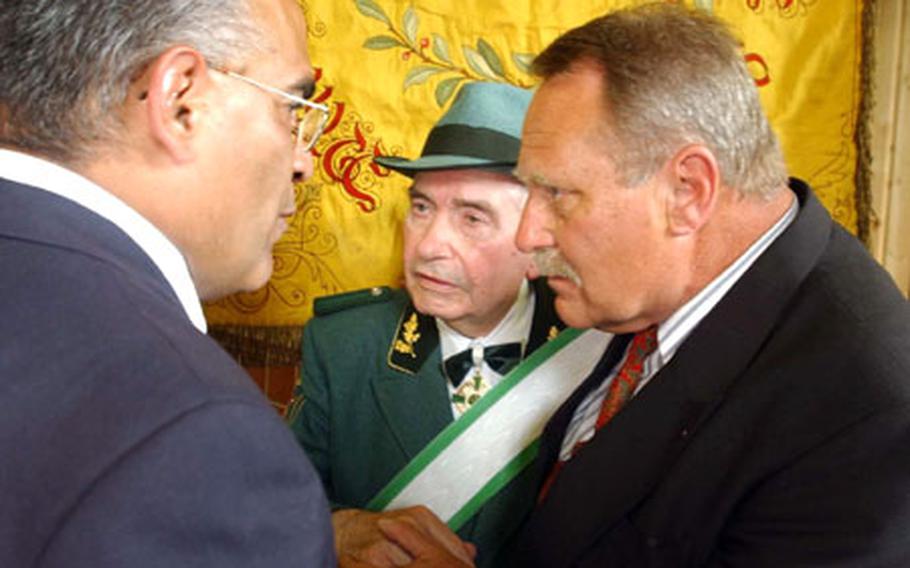 Former GI Manuel Rodriguez, left, and retired Sgt. Maj. Earl Hart, right, bring a flag back to Kofferen, Germany, where they present it to Peter Bongartz, center, a former German soldier who lives in the village.