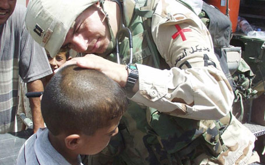 Capt. Kevin Burnham, a physician's assistant with the 2/7 Cavalry Regiment, examines an Iraqi boy's ear during a goodwill visit Friday to Mushada, Iraq, a village 30 miles north of Baghdad.