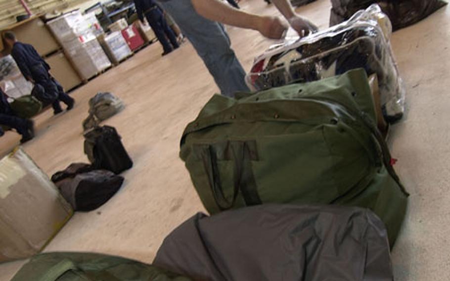 Petty Officer 2nd Class Lee Kersell helps to move sea bags after a three-month deployment on the USS Kitty Hawk.