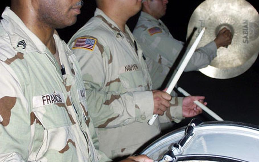 From left, Staff Sgt. Charles Francis of San Antonio, Texas, Sgt. Christopher Nguyen of Orlando, Fla., and Spc. Habacuc Barrera of Mission Viejo, Calif., perform during the 1st Armored Division’s Memorial Day ceremony at Baghdad International Airport on Monday night.