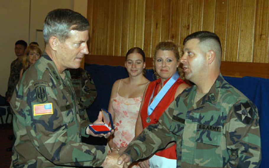 Maj. Gen. John R. Wood presents outgoing 1st Brigade Command Sgt. Maj. Joseph Zettlemoyer with the Legion of Merit in recognition of his service in South Korea while his wife, Tina and daughter Shannon look on.