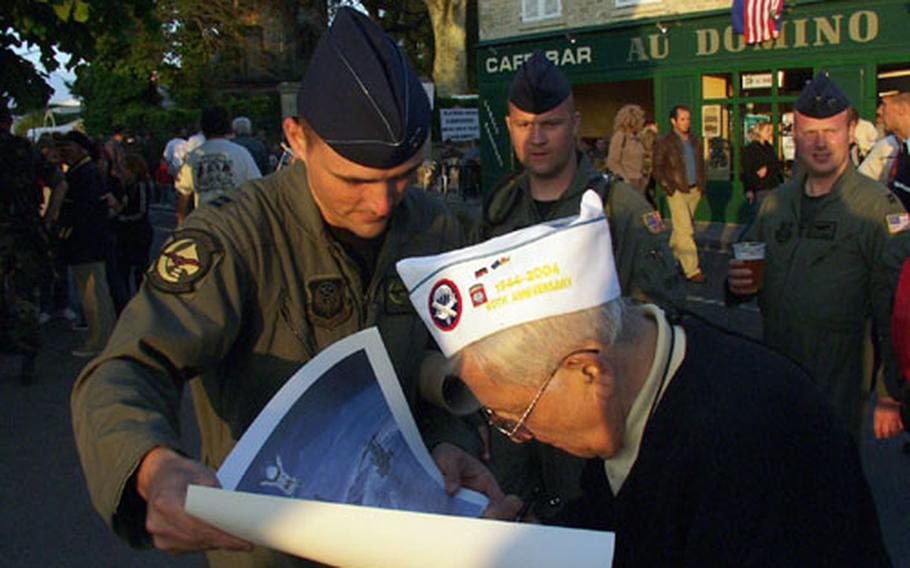 Whether it's autographs or handshakes, World War II D-Day veterans are the real VIPs at this weekend's 60th anniversary ceremonies. On a Friday night in Ste. Mere-Eglise, the first French town liberated by U.S. forces, Air Force Capt. Pat DuBe asks veteran Daniel Bologna to sign a poster for him. Looking on were Tech. Sgt. Bryan Lakin (center back) and Capt. Scott Hartman (far right). The airmen are all members of the 352nd Special Operations Group, 67th Special Operations Squadron at RAF Mildenhall, England.