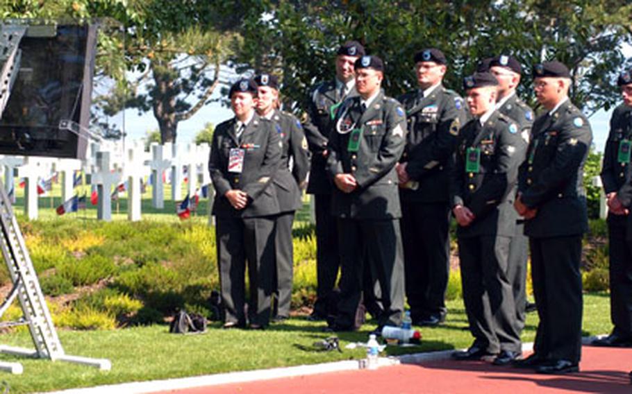 A group of soldiers watches President Bush speak at Normandy American Cemetery on the 60th anniversary of D-Day, on a TV monitor. For many of the thousands of spectators at the ceremony, this was the best view of the president and the event.