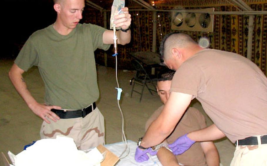 Petty Officer 2nd Class Jason Williams, left, a corpsman with 2nd Medical Battalion's Company A, holds an intravenous bag while a Combat Lifesaver student tapes down the IV on a fellow student's arm during a recent class at Camp Virginia, Kuwait.