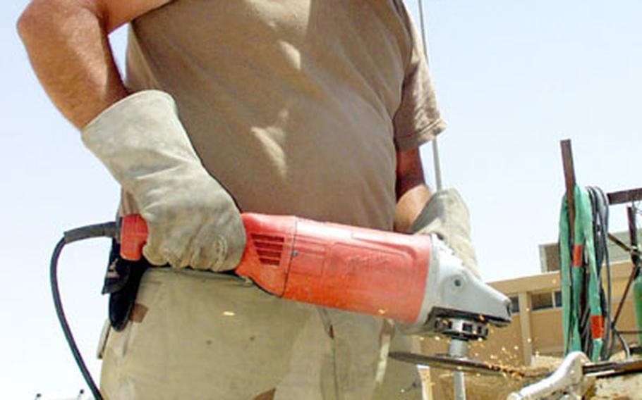Petty Officer 3rd Class Steve Christian, 39, of the 14th Naval Mobile Construction Battalion, grinds brackets to be used to attach armor to Humvees at al-Asad, Iraq.