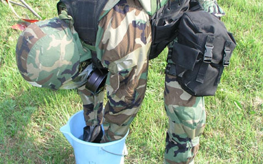 Senior Airman Michael Fink places a mock enemy chemical device in a bucket of water during combat readiness exercise at Osan Air Base, South Korea Wednesday. The weeklong exercise involves U.S. Air Force units around South Korea. Fink is an explosive ordanance disposal airman with the 51st Fighter Wing.