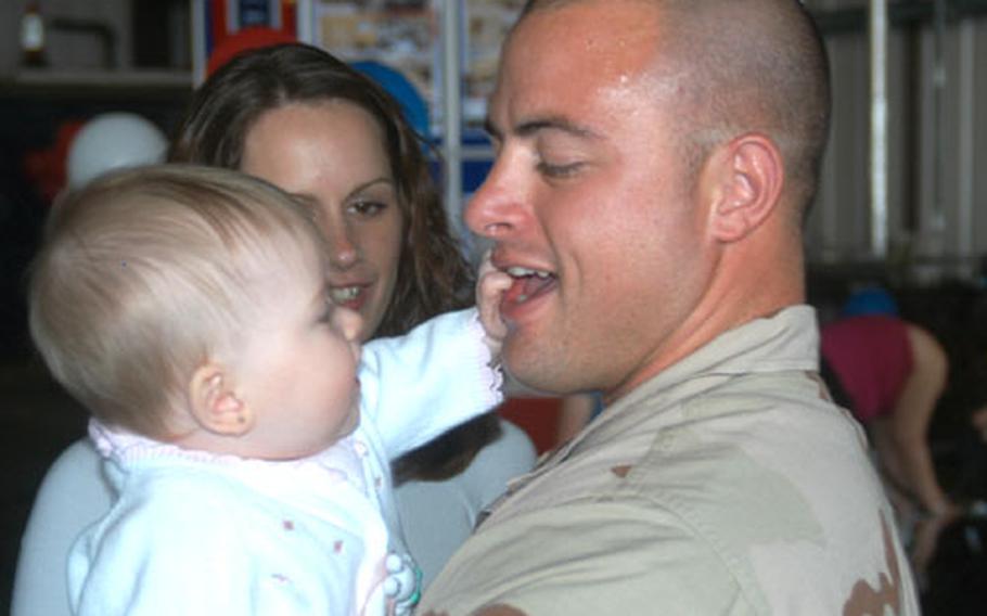 Staff Sgt. Robert Scyoc receives a personal greeting from Lia, 7 months, after returning to RAF Lakenheath, England, Saturday from a three-month tour in the Middle East. Watching is his wife, Amber.