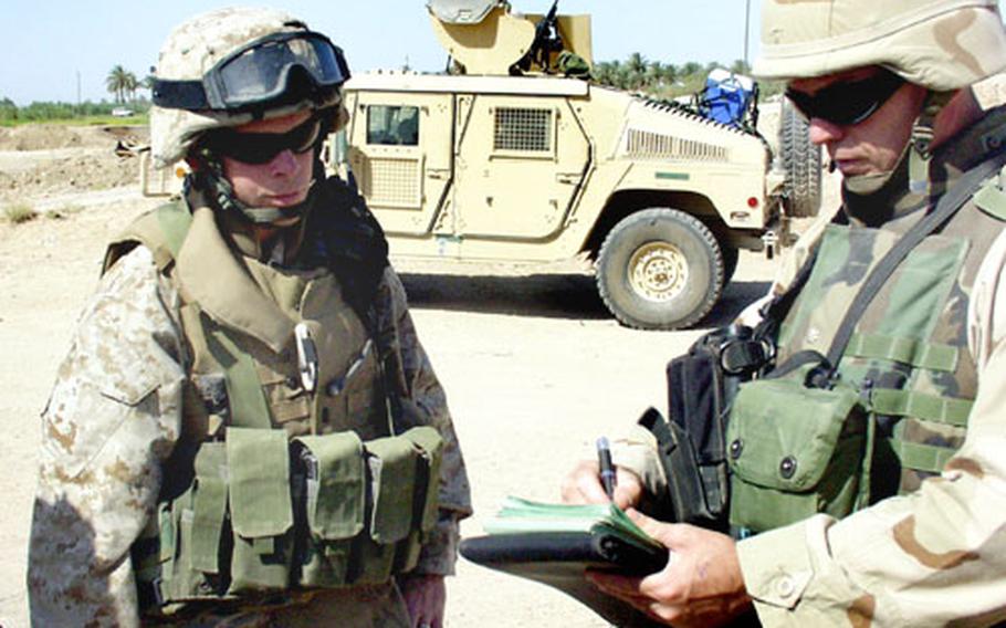 Navy Lt. Cmdr. Joe Stricklin, right, of Greenville, Ga., and Marine 1st Lt. Samuel Cunningham of Indiana, Pa., take notes on the site of a future Iraqi Civil Defense Corps camp about 10 miles southwest of Fallujah, Iraq, during their visit on Saturday. Safety concerns mean the Seabees, who belong to the Navy’s construction division, will spend just one hour appraising the site before loading up and heading out.