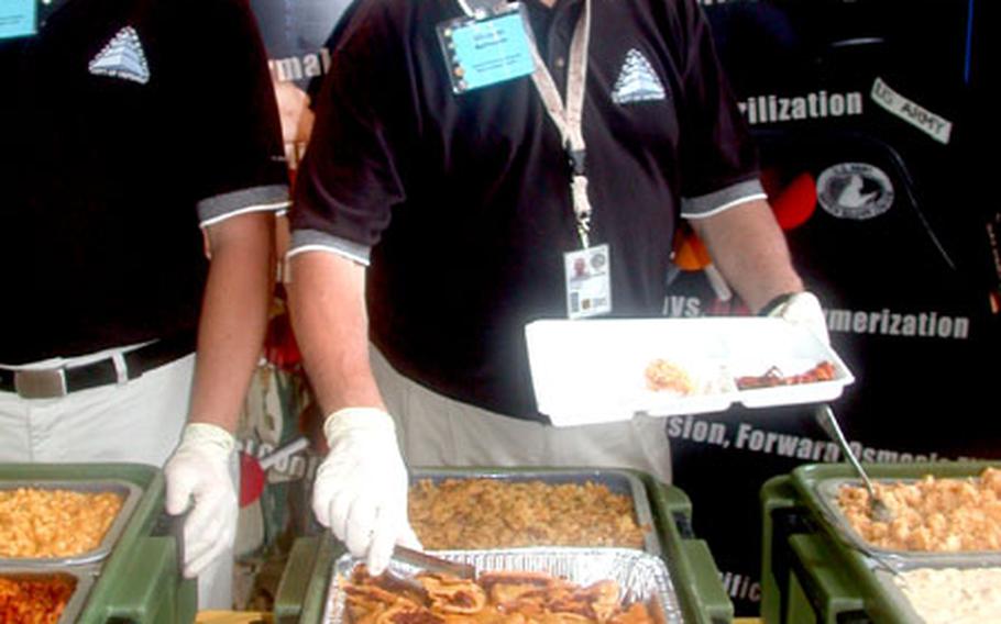 Wesley Long, left, a student employee in DOD's Combat Feeding Directorate, and Mike Acheson, a food technologist for the directorate, dish up samples of the latest hot chow last week on Capitol Hill.