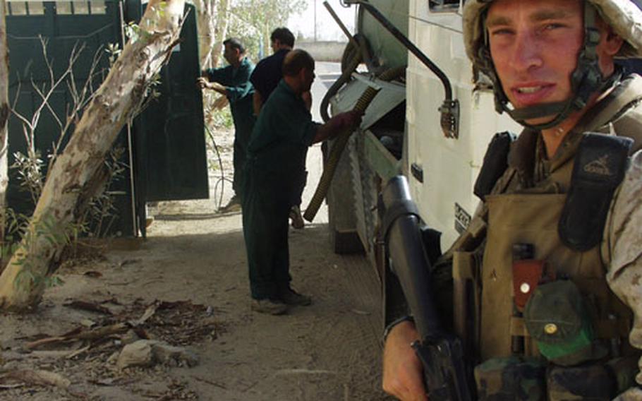 Lance Cpl. Chandler Pierce of Santa Rosa, Calif., and Weapons Company, 2nd Battalion, 1st Marine Regiment, guarding the toilet-cleaning crew as it works its way around Camp Baharia, Iraq.