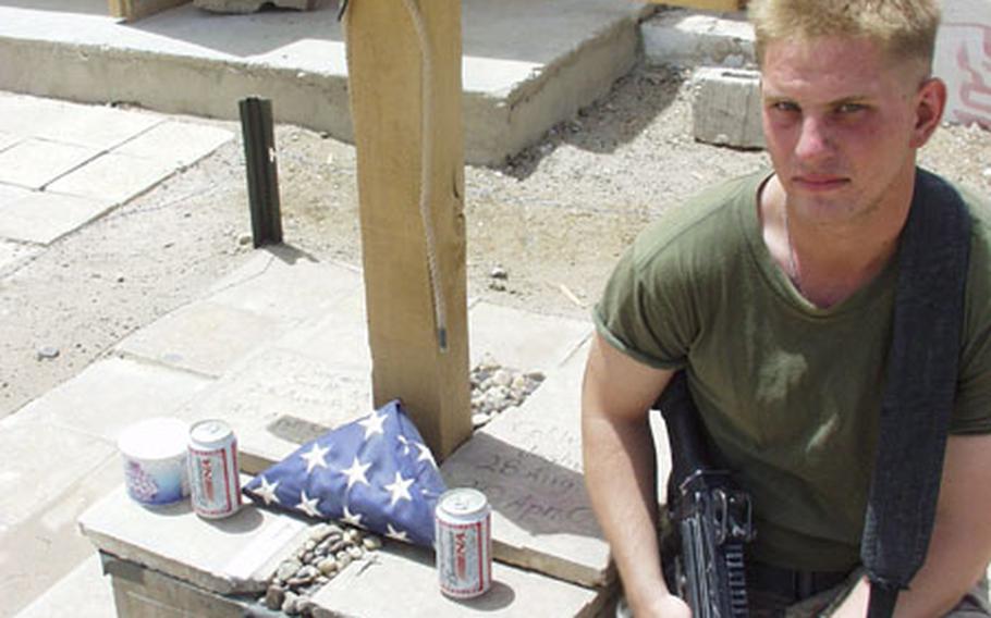 Lance Cpl. Ken Torok of Reading, Pa., of the 2nd Light Armored Reconnaissance Battalion kneels before a memorial for two slain fellow Marines — Cpls. Scott M. Vincent and Joshua S. Wilfong — at Camp Baharia, Iraq. Vincent and Wilfong were killed April 30 by a car bomb while on patrol.