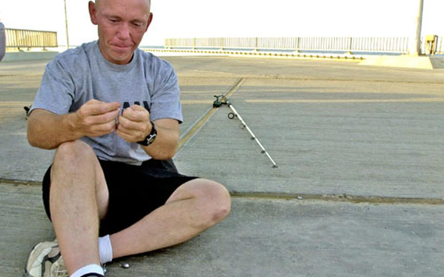 Sgt. Tom Banks, from the Army National Guard's 1244th Tranportation Company, prepares his line before several hours of fishing at a pier in Kuwait.