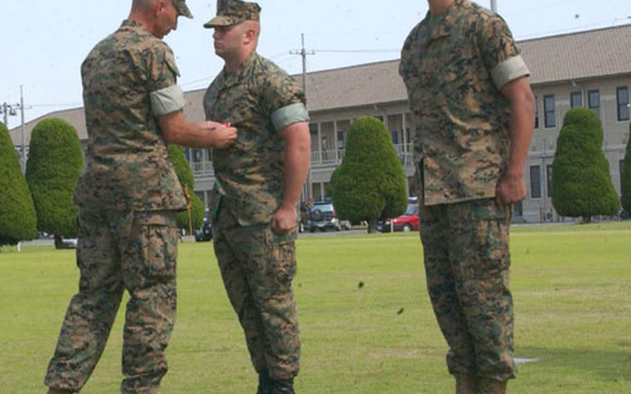 Sgt. Adam Lauritzen (center) and Sgt. Mauricio Guevara (right) combat engineers with Marine Wing Support Squadron 171 at Iwakuni Marine Corps Air Station, Japan, receive the Bronze Star Medal with combat distinguishing device for their service during Operation Iraqi Freedom, from Col. Stephen Fenstermacher, commander of Marine Wing Support Group 17, during a ceremony June 9.
