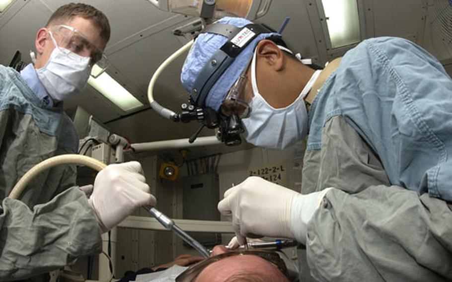 Lt. Ray S. Hovijitra of Indianapolis and his assistant, Dentalman Donald Fulcher, of Portland, Ore., perform a dental exam on a USS Kitty Hawk sailor as part of the ship’s mission readiness plan. The Kitty Hawk Strike Group is currently operating as part of Summer Pulse ’04, the simultaneous deployment of seven carrier strike groups to demonstrate the Navy’s ability to provide credible combat power throughout the world. Summer Pulse is the Navy’s first deployment under its new Fleet Readiness Plan.