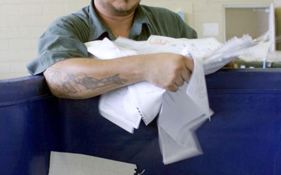 Jeffrey Strain, a materials handler for the recycle center on Camp Foster, Okinawa, separates and throws white office paper into a recycle bin at the Foster Recycle Center, Thursday.