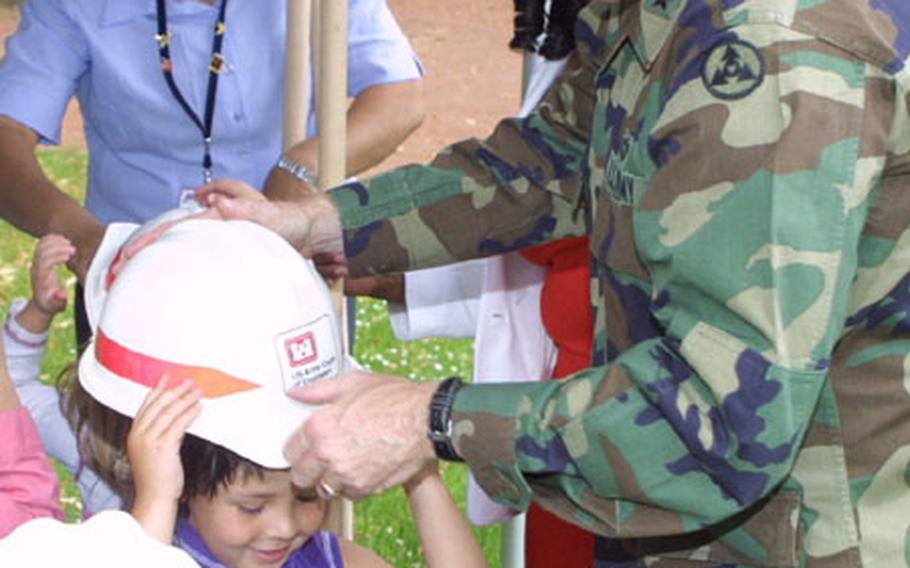 Brig. Gen. Vincent E. Boles, commander of the 3rd Corps Support Command, helps a child don a hard hat to get ready to break the ground for a new $3.6 million Child Development Center on Wiesbaden Army Airfield on Thursday. The new CDC, a project being managed by U.S. Army Corps of Engineers, is slated for completed in December 2005.