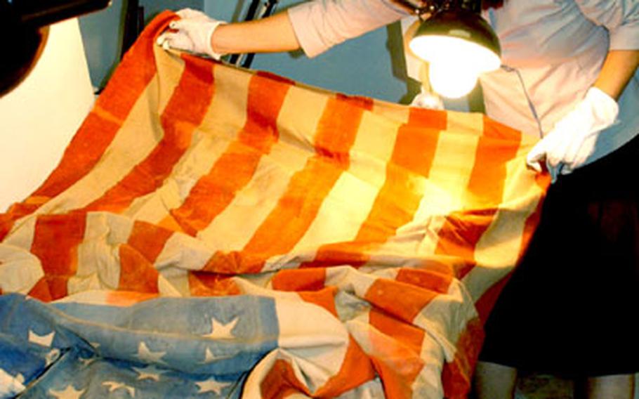 Museum technician Incha Koslosky prepares a U.S. flag used for funerals of Allied POWs during World War II for shipment to Arlington National Cemetery, where it will be used during its owner's funeral.
