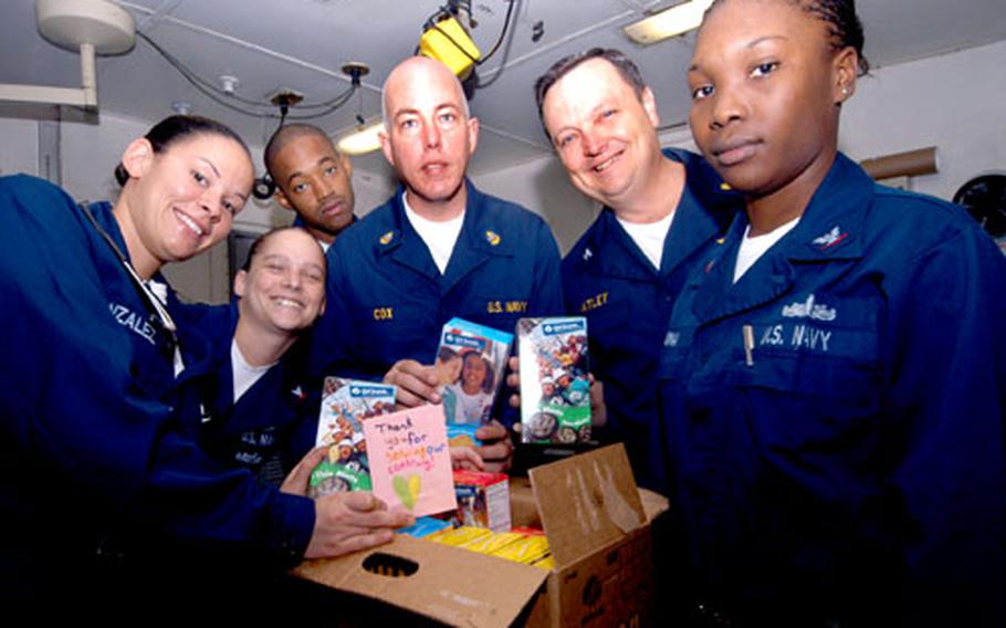 Sailors from USS John F. Kennedy's medical department hold up boxes of cookies and hand-written notes sent to the ship by Girl Scouts througout the United States.