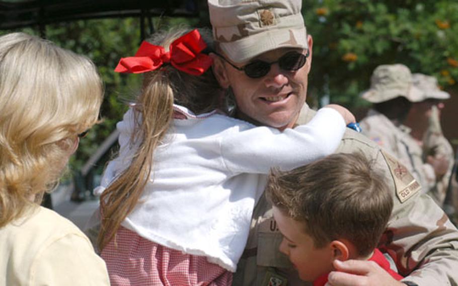 Maj. Donnie Walker, of the 16th Engineer Battalion, gets a welcome-home hug from daughter, Dani, and son, Jordan, as wife, Kirsty, watches at left. About 130 Giessen, Germany, based soldiers arrived home from Iraq on Sunday morning.