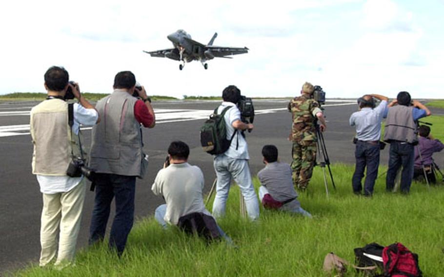 Members of the press cover the Iwo Jima landing of an F-18F Super Hornet on Monday.
