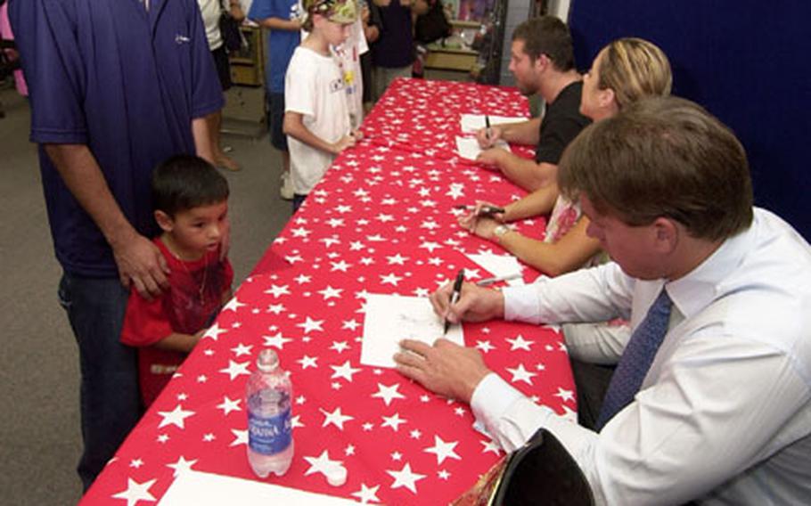 Tech. Sgt. Alex Sernarojas (left) with his son Adrian, age 3, get an autograph from World Wrestling Entertainment Champion John Bradshaw Layfield in the Power Zone at Yokota Air Base.