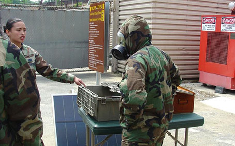 At Osan Air Base, South Korea, Airman 1st Class Karen-Ann Santiago of the 51st Civil Engineer Squadron, guides an airman through training last month in how to safely move from one part of an airbase to another under varied levels of chemical hazard.