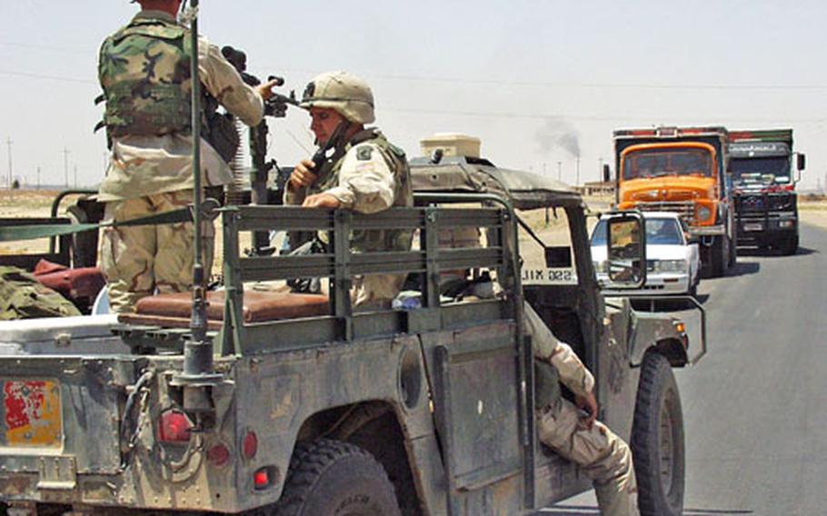 July, 2003: Soldiers with the 173rd Airborne Brigade’s Combat Support Company block a road on the outskirts of Kirkuk, Iraq, while experts blow up unexploded ordnance found in the area.