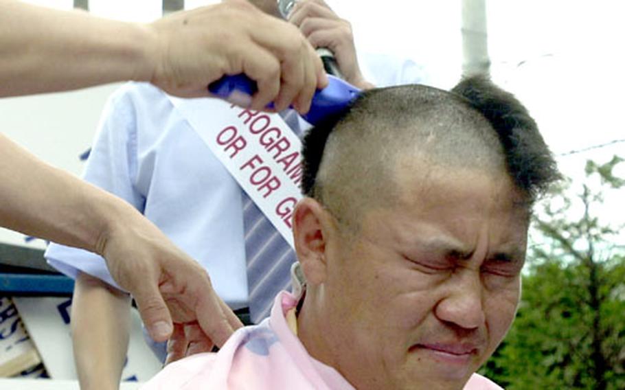 Lim Jong-han, a property owner, winces as other demonstrators protesting a new Army housing program shave his head Tuesday outside the gates of Yongsan Garrison in South Korea. More than 600 landlords and real estate agents protested the program, which will give landlords a deposit rather than monthly rent, driving down rental profits, they say.