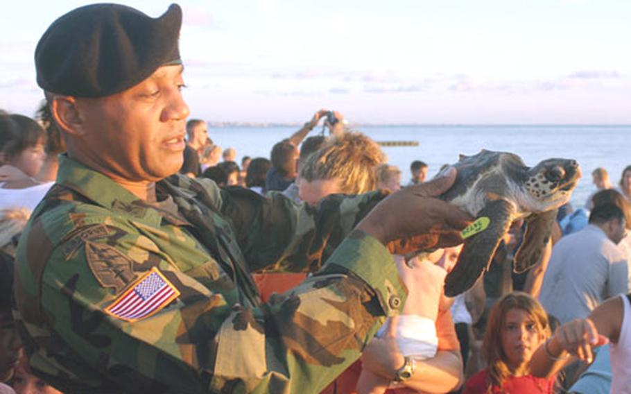 Col. Anthony L. Williams, commander of the 10th Area Support Group, holds “Betty,” a one-year-old turtle, before releasing her into the water at Torii Station's beach Tuesday.