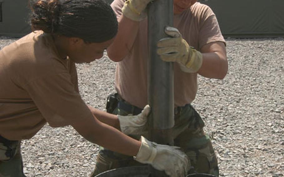 Staff Sgt. Lakeisha El Hallaoui, left, and Tech. Sgt. Ernest Peralta, of Ramstein&#39;s 435th Services Squadron, install cooking equipment Thursday during the Silver Flag training exercise at Ramstein Air Base, Germany. About 200 airmen from U.S. Air Forces in Europe and beyond are training to deploy to a bare base.