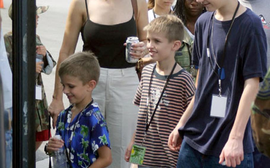 Left to right, Keith and Lisa Hunt and their three sons, Andrew Bryan, 6, Nathan Bryan, 8, and Brandon Bryan, 15, board a bus Saturday at Kadena Air Base, Okinawa, for Operation KUDOS, or Kids Understanding Deployment Operations. Kids attended briefs and demonstrations to help them understand what their parents go through when they prepare to deploy.