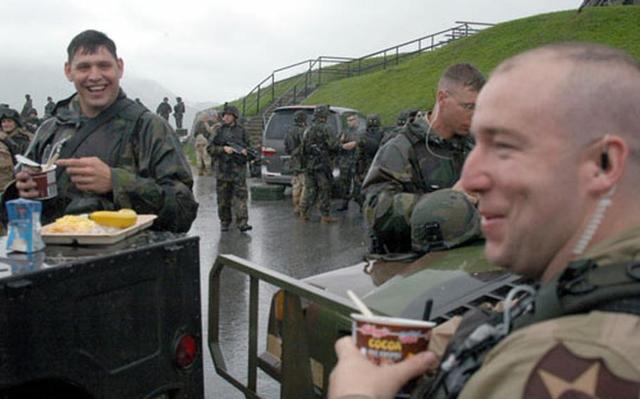 From left, Sgt. Joseph Staver and Staff Sgt. Sean Huey enjoy a soggy breakfast during training for deployment to Iraq.