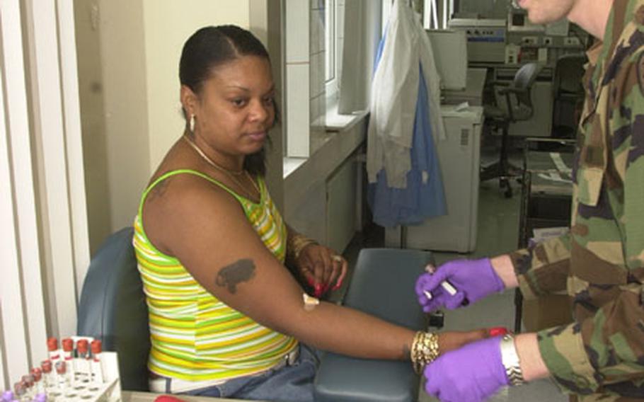 Sgt. Donald Mason, U.S.A Health Clinics, Baumholder Health Clinic, prepares to take blood from April Roserie, 34, on Tuesday. She was one of two patients early in the afternoon. But, Mason said, he's expecting business to pick up in about a month when most of the troops are back in Baumholder.