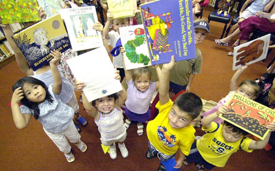 Yokosuka Naval Base kids hold up newly-donated books at the base library. The books were donated by the Alpha Delta Kappa sorority.