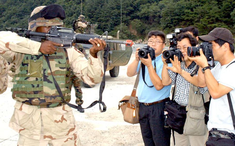South Korean journalists photograph a soldier from the 2-17 Field Artillery Regiment in Warrior Valley.
