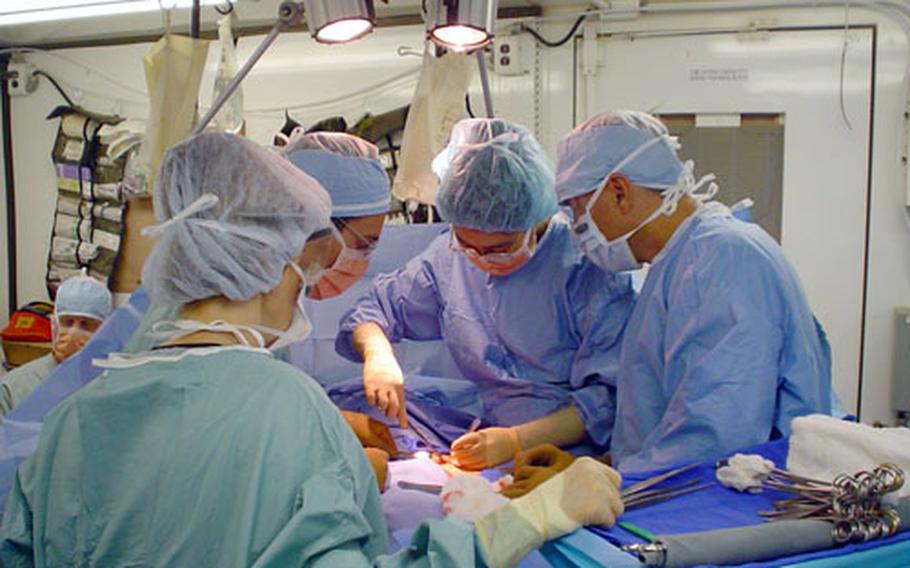 Maj. Li-ing Chang, center, a general surgeon at Misawa Air Base, operates on a patient at Camp Sather in Baghdad International Airport, where she was deployed this spring for three months.